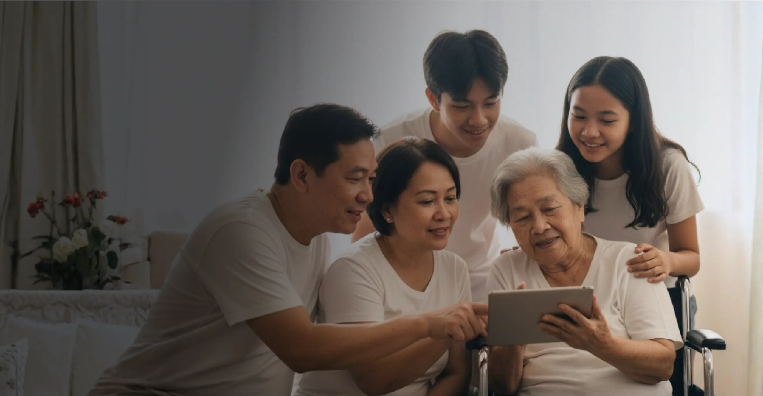 A Filipino family gathered around their grandmother, looking at a tablet together
